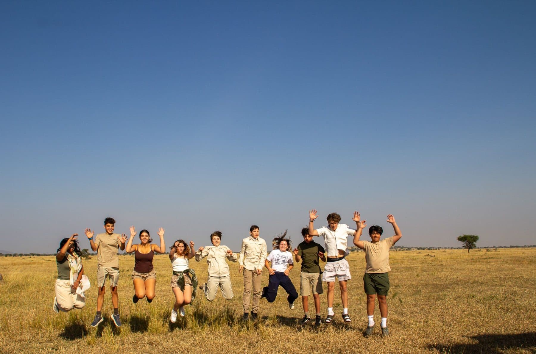 The travel group jumping on the open plain in the Serengeti
